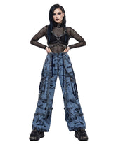 Woman wearing wide leg cargo jeans, baggy cargo pants women, tie-dye denim wash, front view with harness top