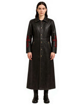 Black leather gothic trench coat with red cross embroidery on sleeves, button-down front, and full-length silhouette