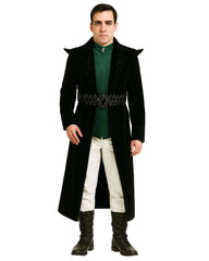 Man wearing black velvet jacquard spiked studded leather jacket with green shirt, white pants, and black boots
