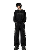 Men's baggy cargo pants in black with skull graphic pockets and chain detail, front view