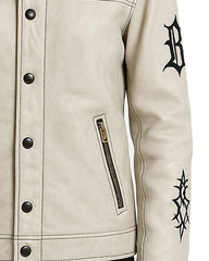 Close-up of Gothic cream leather jacket with black embroidered sleeve, snap-neck collar, button-front closure, and zippered pocket