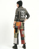 Person wearing a studded leather jacket with 'Chaos Punk' text and patchwork pants on a white background