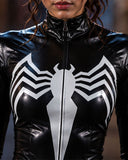A close-up of a person wearing a glossy black latex or faux-leather bodysuit with a large white spider emblem on the chest and a front zipper.