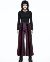 Woman wearing a black top and red and black striped pants on a white background