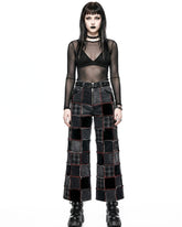 Person wearing a black sheer top and patchwork pants on a white background