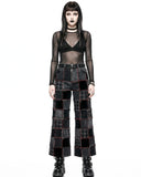 Person wearing a black sheer top and patchwork pants on a white background
