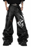 Gothic leather pants for men in black with wide-leg fit, leather-look finish, bold front graphic detail, and oversized alternative streetwear styling shown in lifestyle front and back view.
