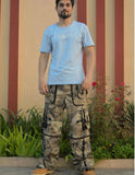 Man wearing Trippprs Camo Cargo Pockets Baggy Pants with a light blue t-shirt outdoors