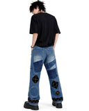 Black patchwork denim jeans with distressed finish, multi-pocket utility design, and wide-leg streetwear fit.