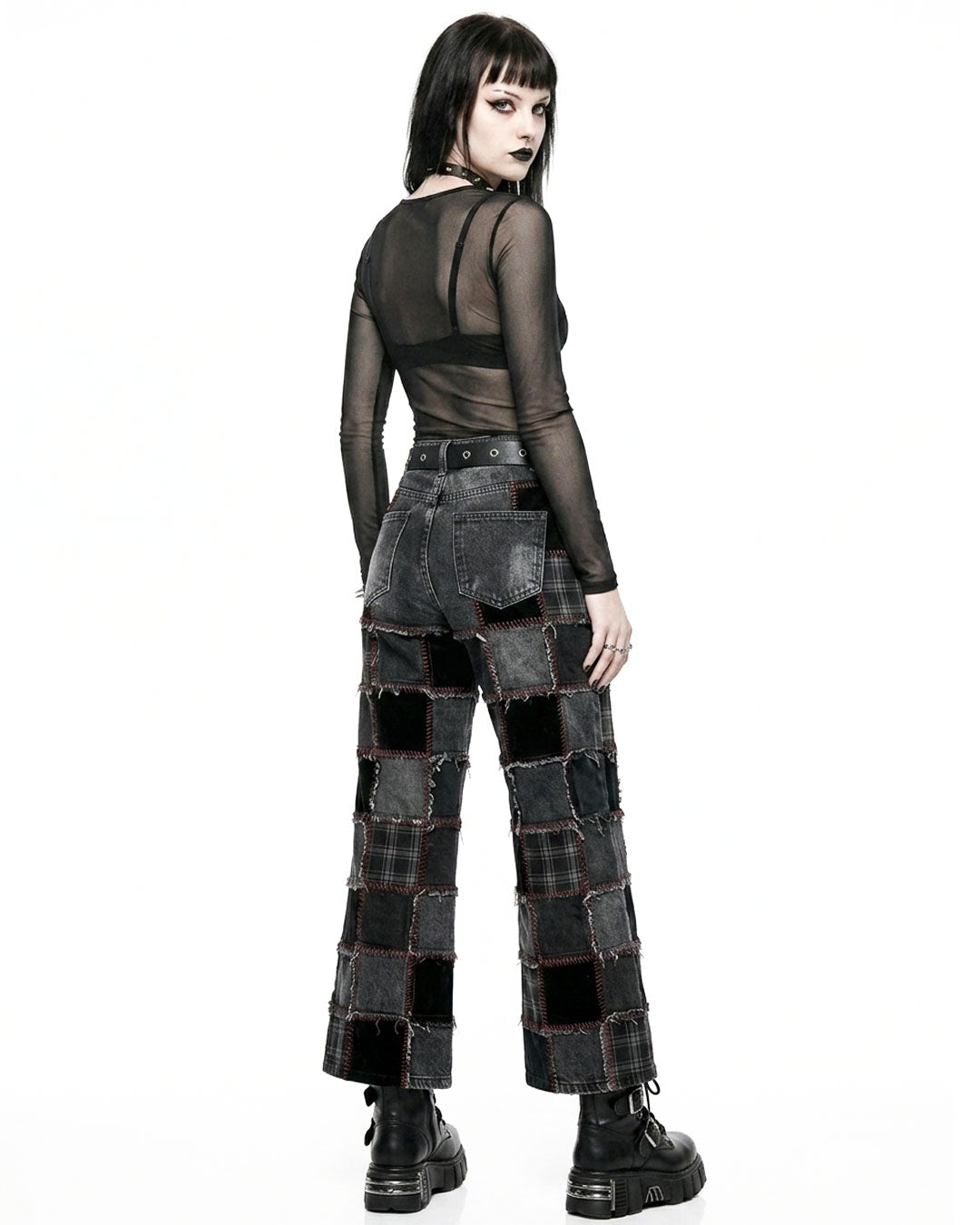 Person wearing a black, sheer top and patchwork pants on a white background