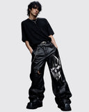 Men's black leather-look gothic pants with oversized silhouette and graphic detail