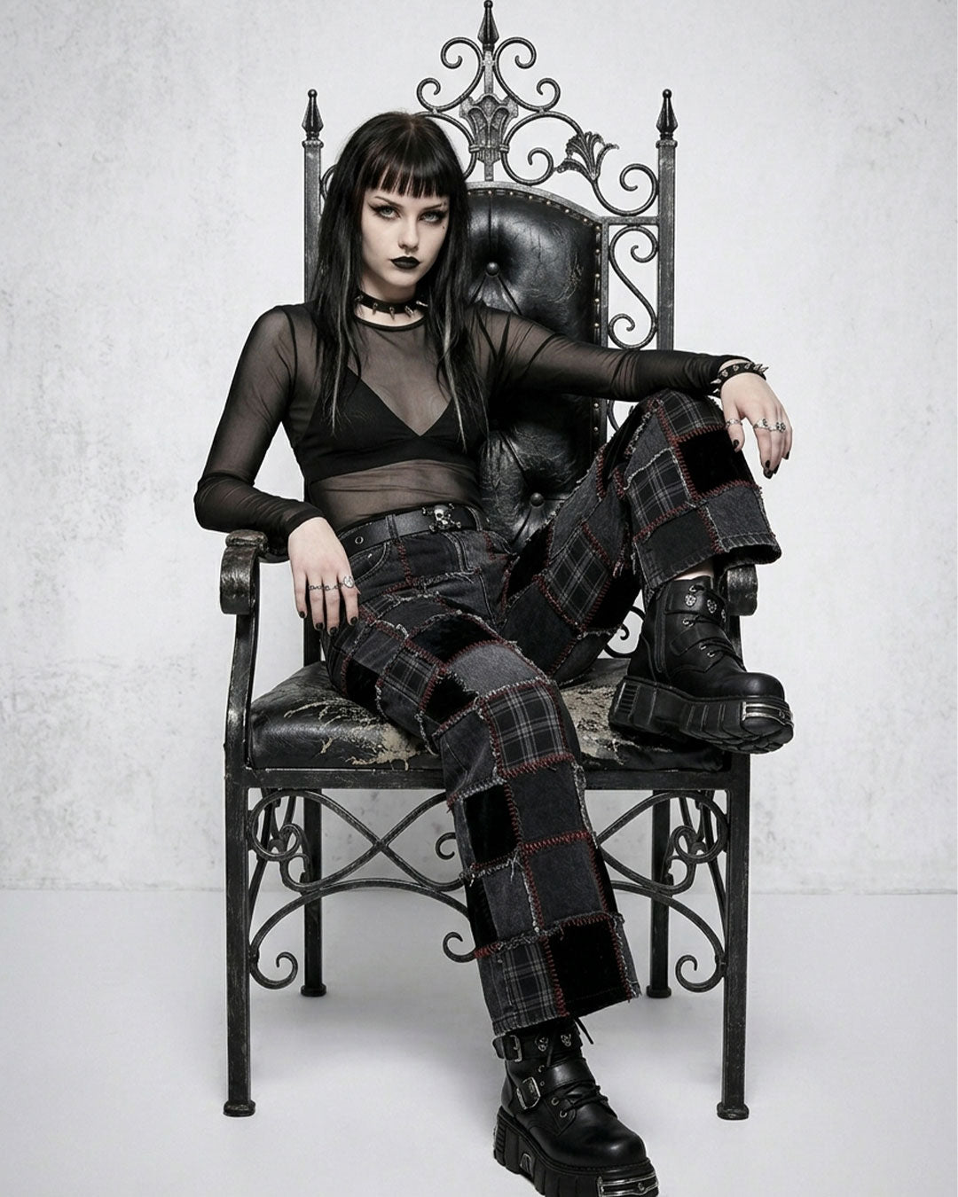 Person wearing a gothic outfit sitting on an ornate chair.