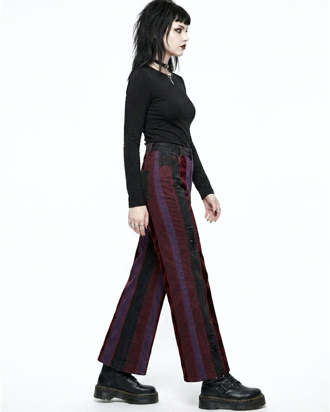 Person wearing a black long-sleeve top and striped pants on a white background
