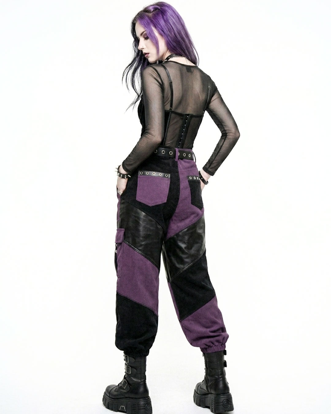 Person wearing a black and purple outfit with a sheer top on a white background