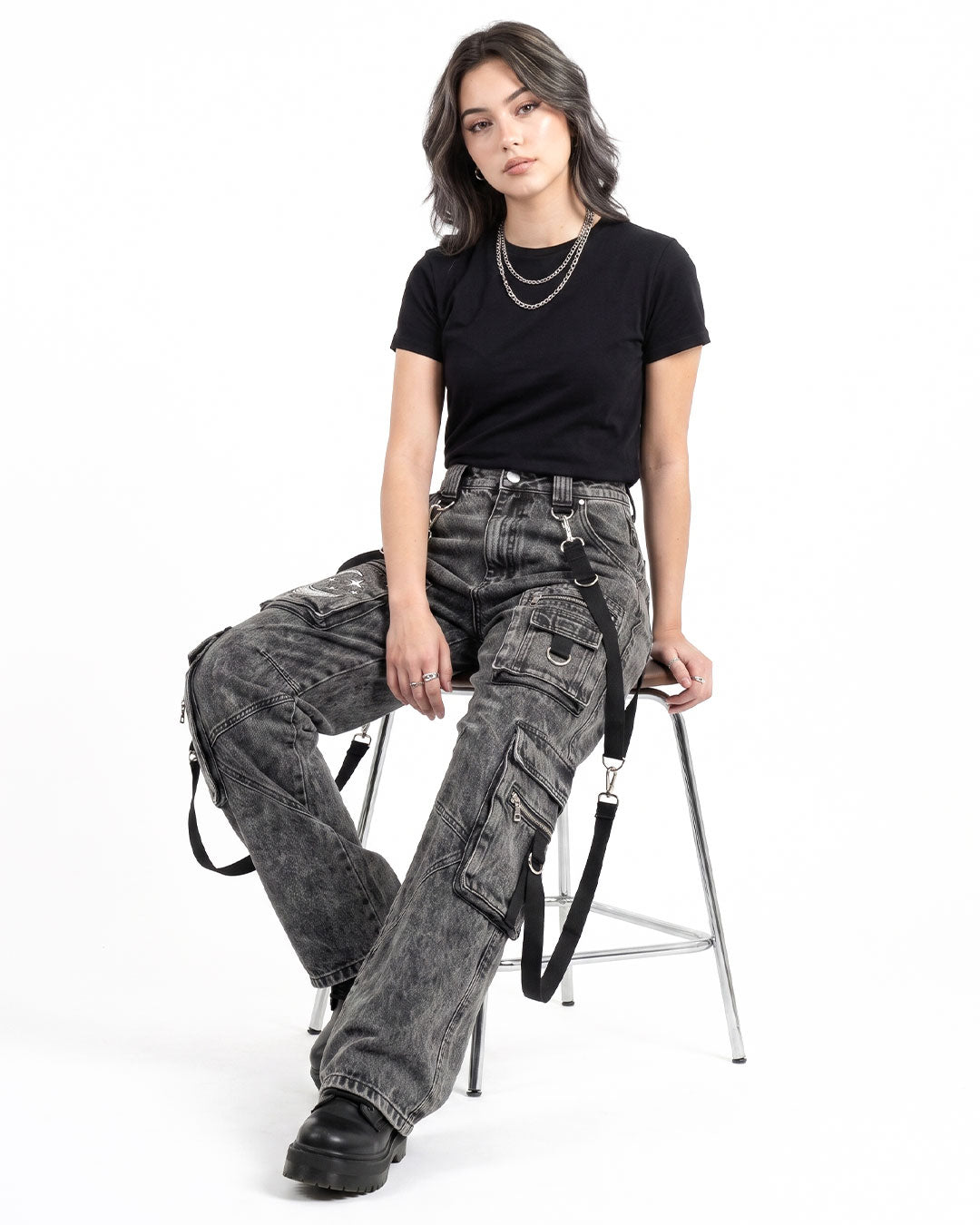 Model wearing Baggy Cargo Jeans Women in a sitting pose showcasing washed black womens cargo jeans with a wide leg fit.