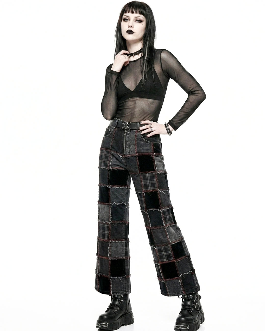 Person wearing a black sheer top and patchwork pants on a white background