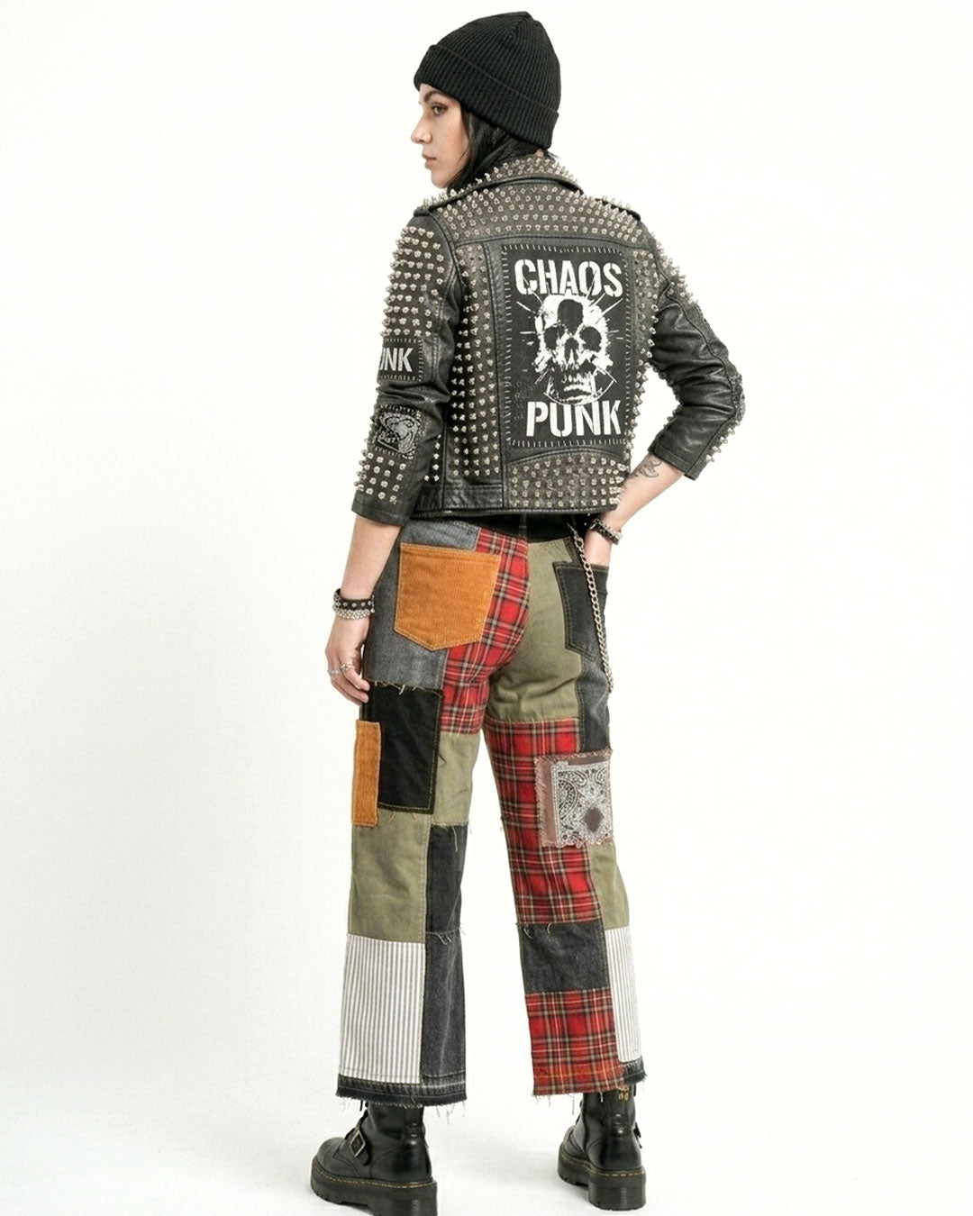 Person wearing a studded leather jacket with 'Chaos Punk' text and patchwork pants on a white background