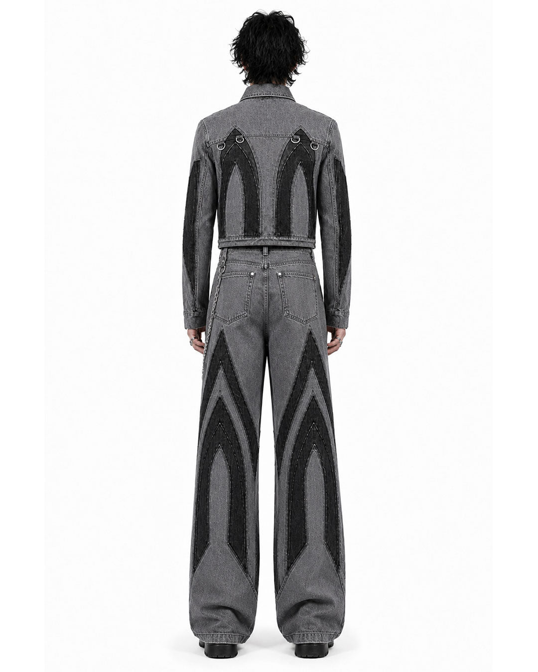 Back view of men’s Gothic Cathedral double denim set with pointed black panels and wide-leg grey jeans