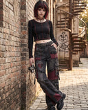 Model wearing women's baggy cargo pants in a gothic streetwear outfit while posing against a wall, showcasing stylish goth cargo pants.