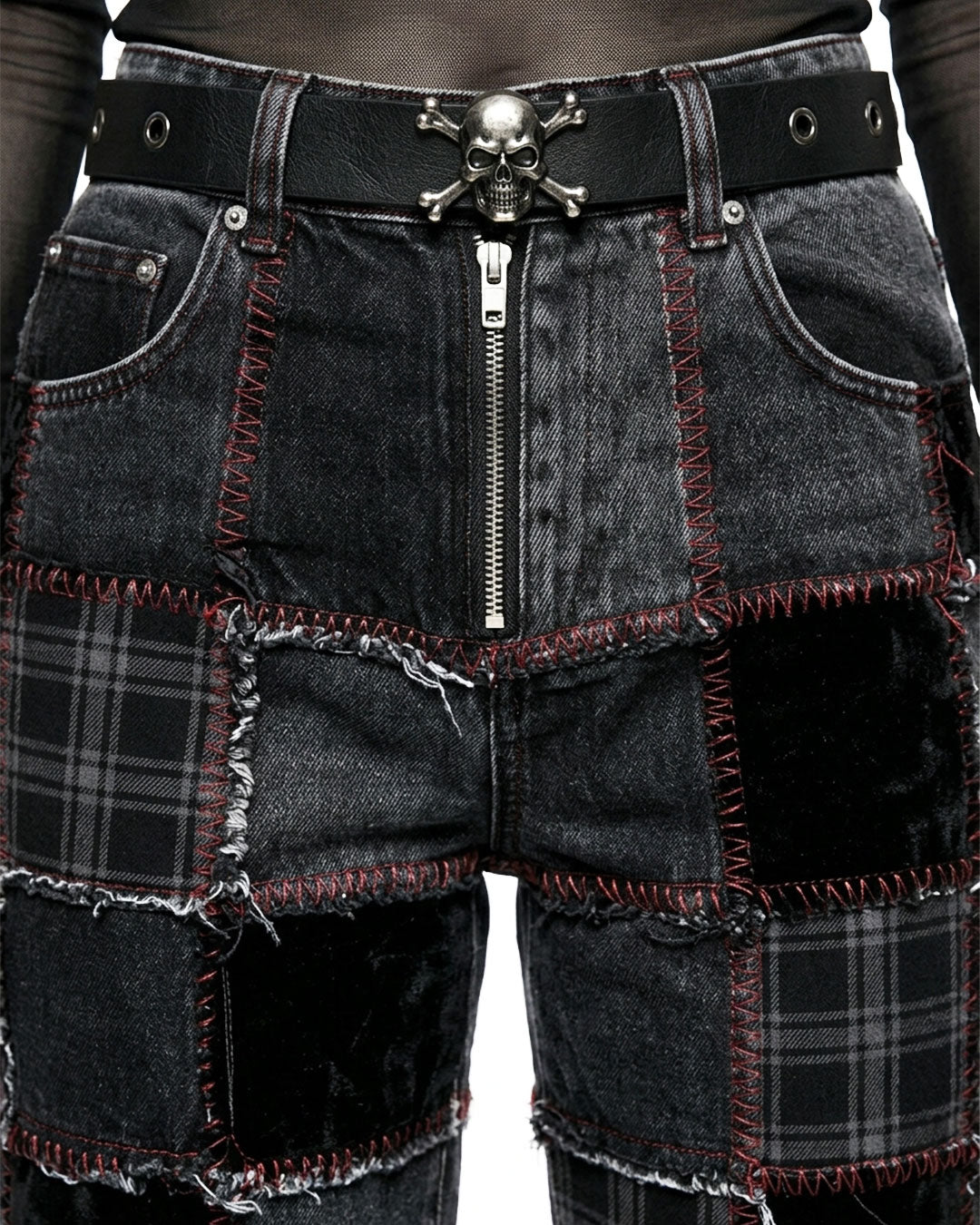 Black patchwork shorts with a skull belt buckle on a plain background