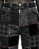 Black patchwork shorts with a skull belt buckle on a plain background