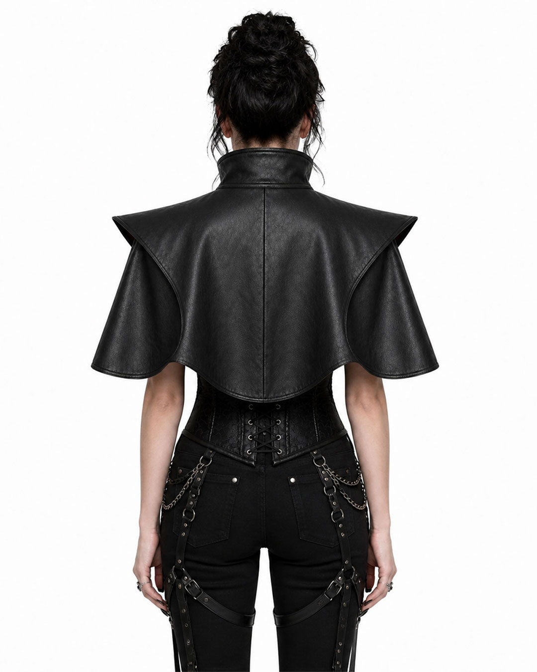 A model shown from the back wearing a black faux-leather gothic cape top with dramatic shoulder flaps, paired with black pants and a corset-style waist piece, against a plain white background.