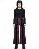 Woman wearing a black top and red and black striped pants on a white background