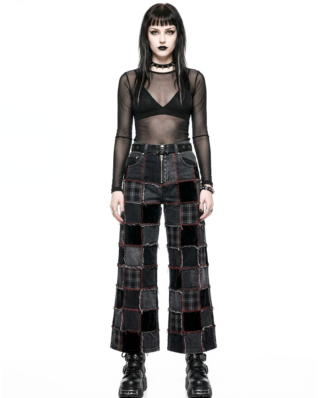 Person wearing a black sheer top and patchwork pants on a white background