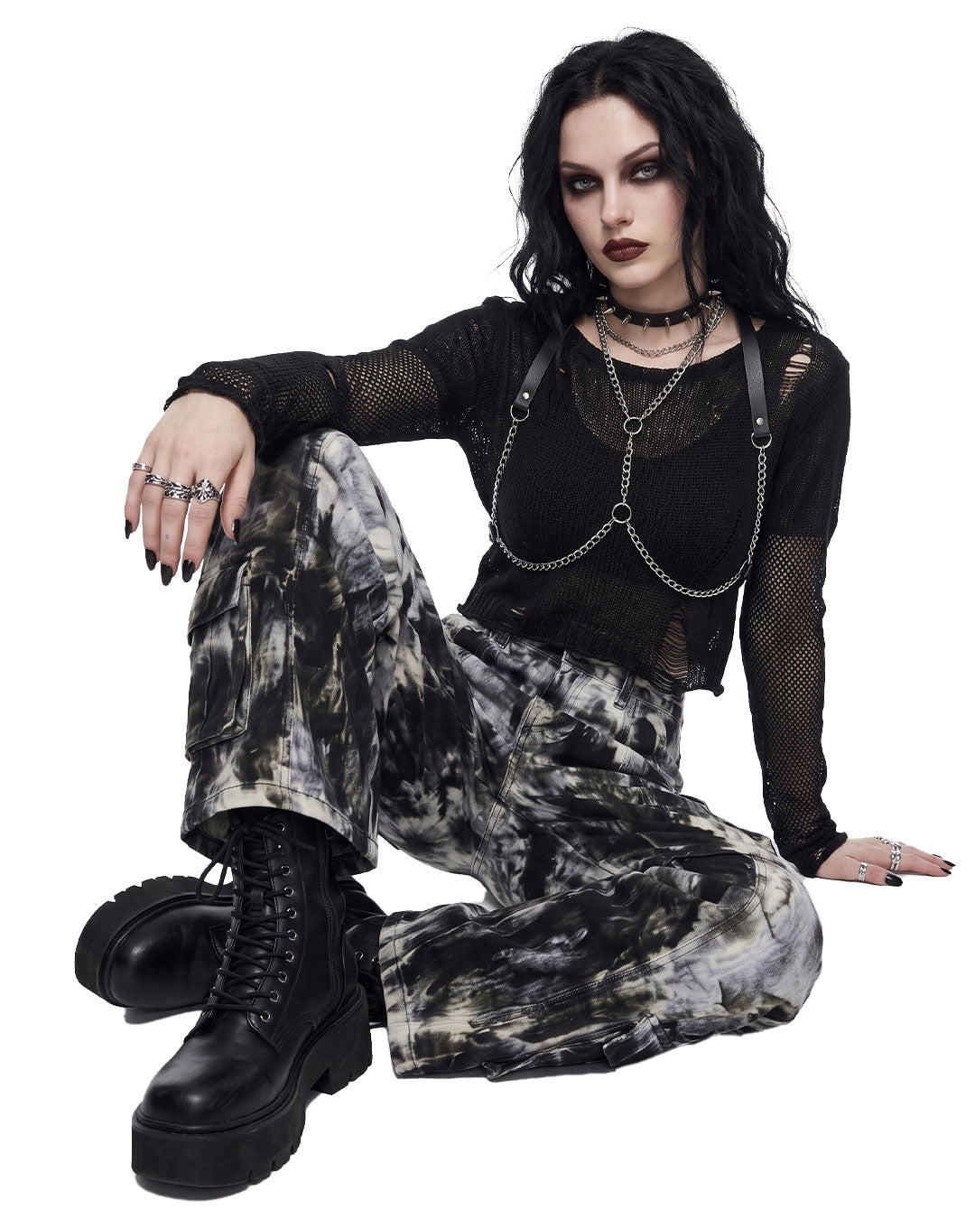 Model seated while wearing women’s tie dye wide leg cargo pants with utility pockets.