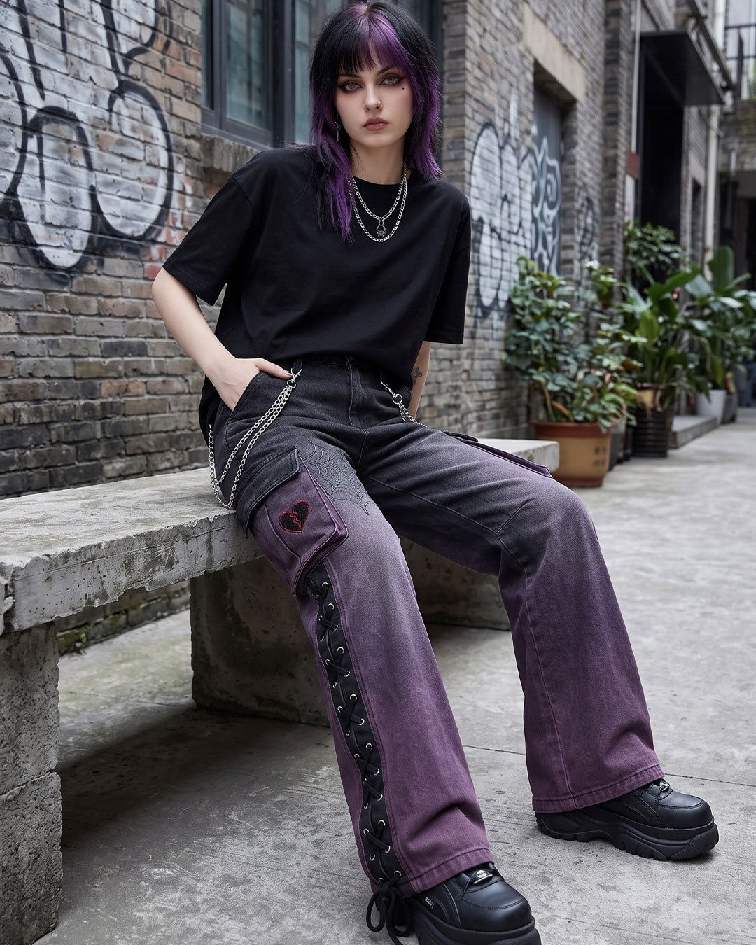 Model sitting in wide leg cargo pants with chain detail and heart embroidery