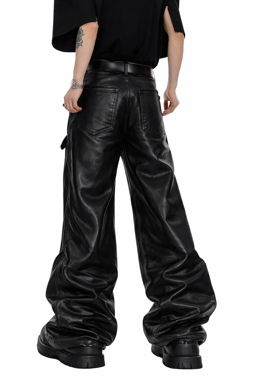 Gothic leather pants for men in black with wide-leg fit, leather-look finish, bold front graphic detail, and oversized alternative streetwear styling shown in lifestyle front and back view.