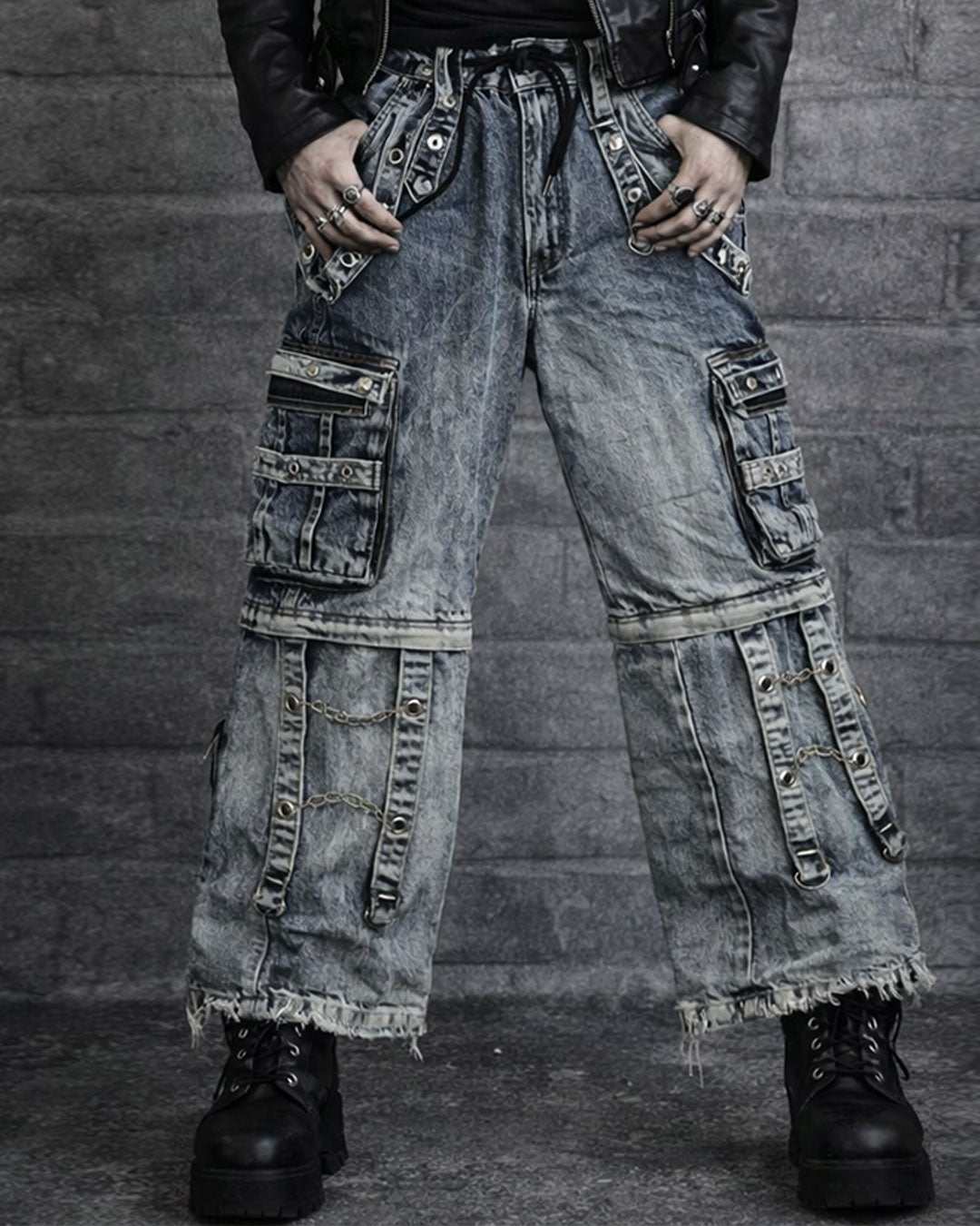 Men's black cargo jeans with baggy fit, multiple utility pockets, strap details, and washed dark finish shown in front and back view on model.