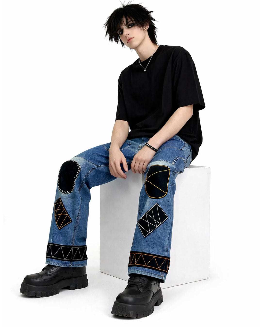 Black patchwork denim jeans with distressed finish, multi-pocket utility design, and wide-leg streetwear fit.